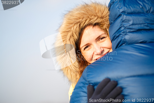 Image of happy pair of male and female embracing ain winter outdoors