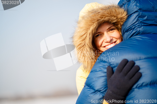 Image of happy pair of male and female embracing ain winter outdoors