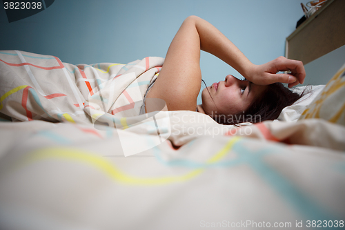 Image of Side view of a sleepy young woman suffering from headache with eyes closed in bed at home