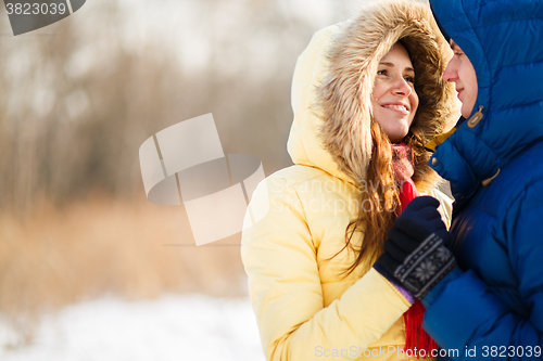 Image of happy pair of male and female embracing ain winter outdoors