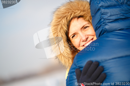 Image of happy pair of male and female embracing ain winter outdoors