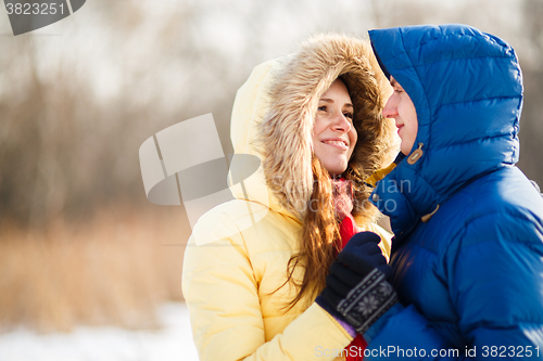 Image of happy pair of male and female embracing ain winter outdoors