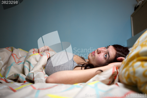 Image of Young woman lying in bed suffering with insomnia  Noisy neighbour, stress, alarm sound, prevent from sleep concept