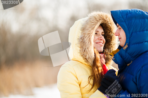 Image of happy pair of male and female embracing ain winter outdoors