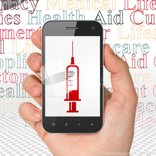 Image of Medicine concept: Hand Holding Smartphone with Syringe on display