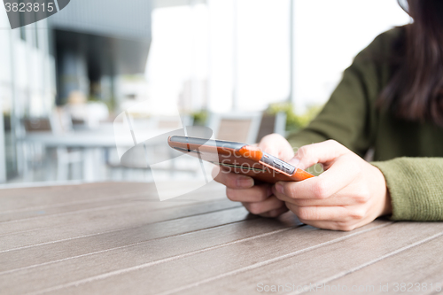 Image of Woman using cellphone at outdoor cafe