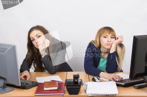 Image of Two young employee of the office behind a desk looking sadly into the frame