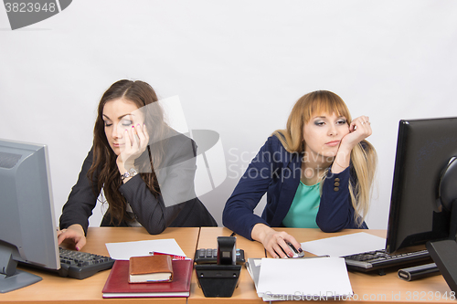 Image of Two young office employee tired of working at computers