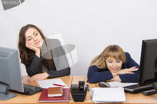 Image of Two young office worker sleeping on the job