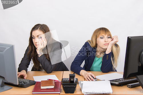 Image of Two young employee of the office behind a desk looking sadly into the frame