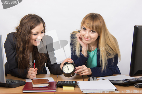 Image of  Two girls in the office happily waiting for the end of the working day