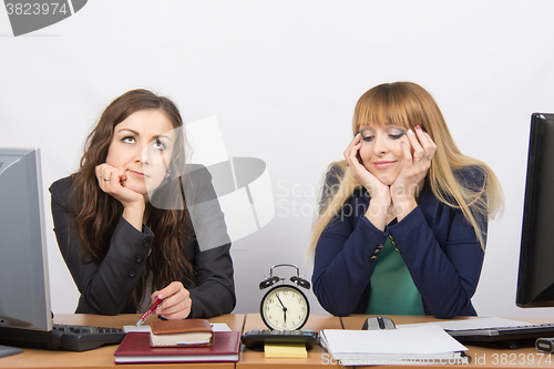 Image of Two employee in the office waiting for the end of working hours on the clock