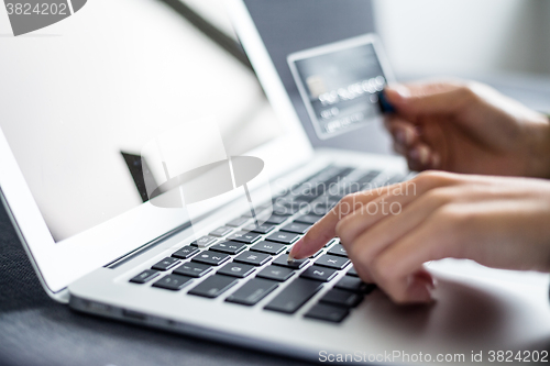 Image of Woman holding credit card and using computer for online shopping