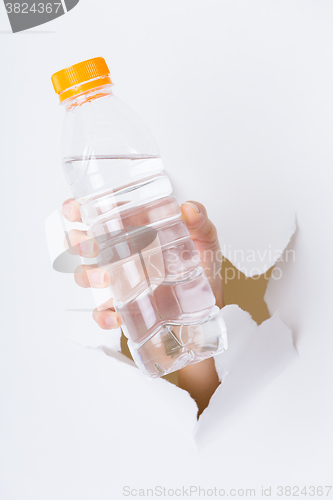 Image of Woman hand with bottle of water through a hole in paper