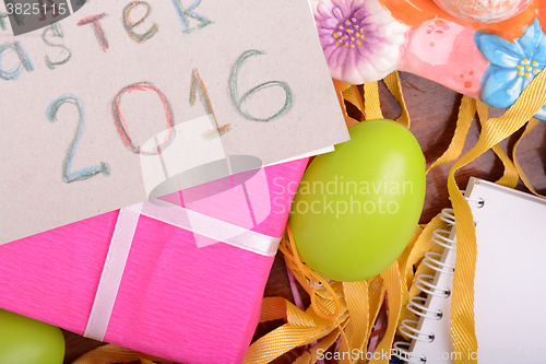 Image of Easter background with colorful eggs and yellow tulips over white wood. Top view with copy space