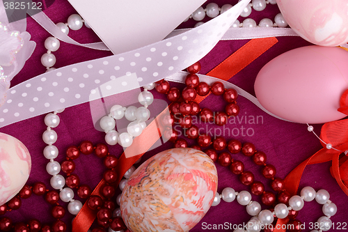 Image of Painted Easter eggs decorated with flowers with pearls in a basket on an old table