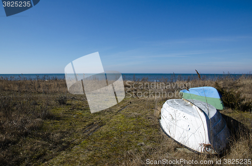 Image of Small rowing boats up-side-down by the coast