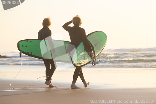 Image of Surfers on beach with surfboard.