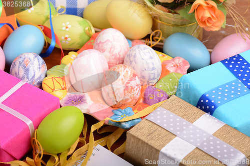 Image of Easter background with colorful eggs and yellow tulips over white wood. Top view with copy space