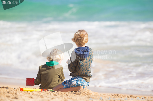 Image of Boys playing with toys on beach.