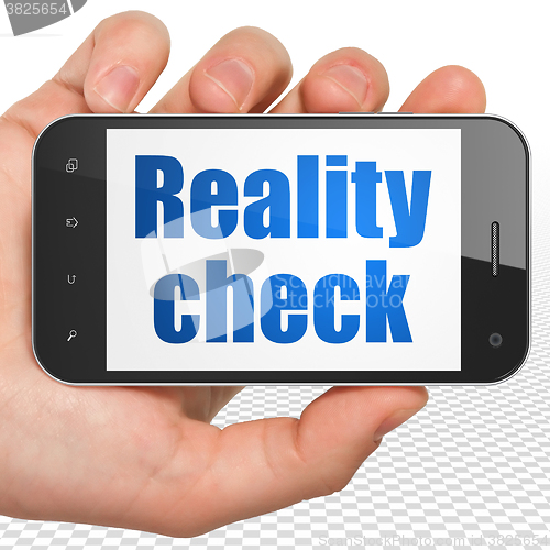 Image of Finance concept: Hand Holding Smartphone with Reality Check on display