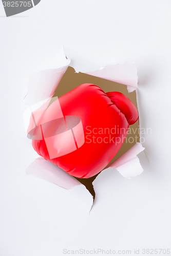 Image of Hand through the hole in paper with boxing gloves