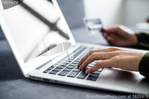 Image of Hands holding credit card and using laptop