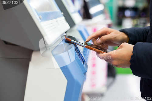 Image of Woman using cellphone for paying on machine