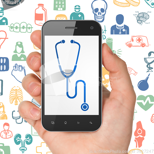 Image of Health concept: Hand Holding Smartphone with Stethoscope on display