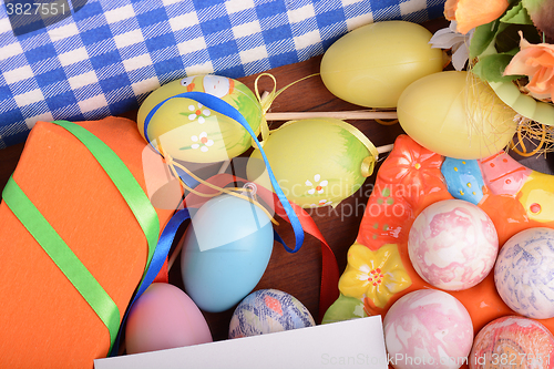 Image of Easter background with colorful eggs and yellow tulips over white wood. Top view with copy space
