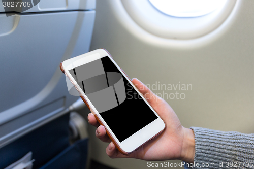 Image of Holding digital mobile phone at airplane