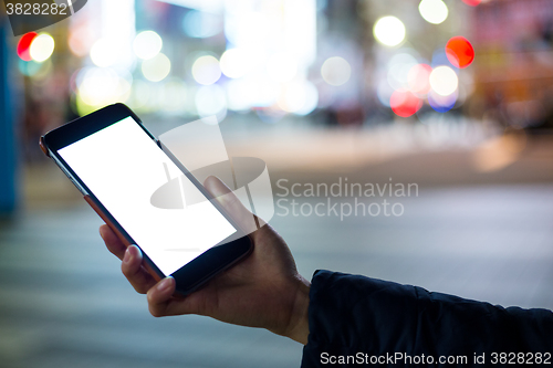Image of Woman hand holding cellphone at city night