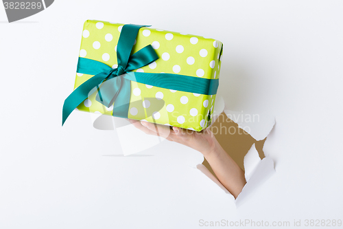 Image of Hand through the hole in paper with present box