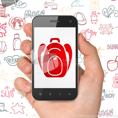 Image of Vacation concept: Hand Holding Smartphone with Backpack on display