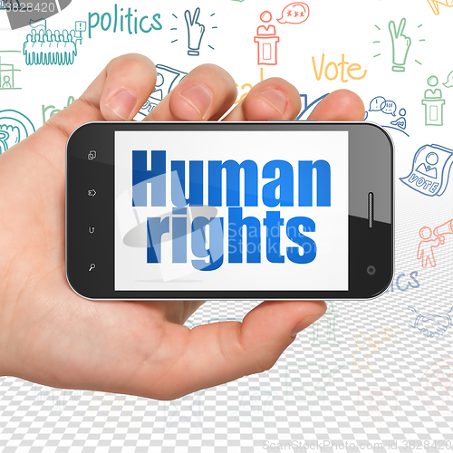 Image of Politics concept: Hand Holding Smartphone with Human Rights on display