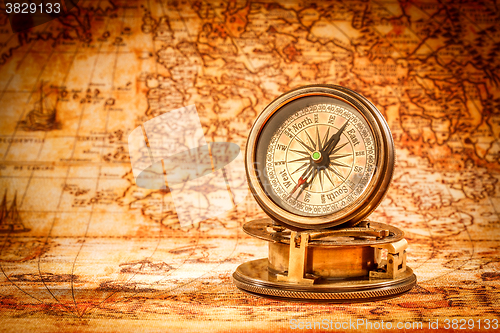 Image of Vintage compass lies on an ancient world map.