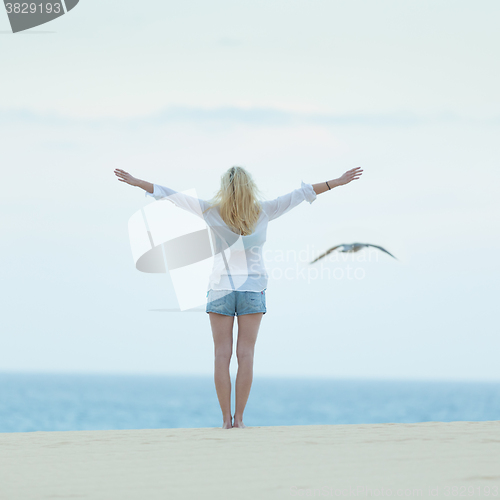 Image of Free woman enjoying freedom on beach at dusk.