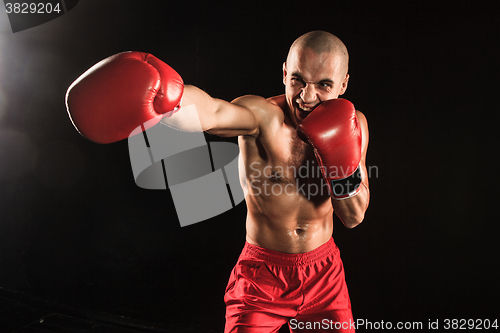 Image of The young man kickboxing on black
