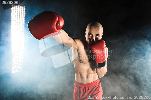 Image of The young man kickboxing in blue smoke