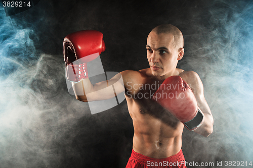 Image of The young man kickboxing in blue smoke