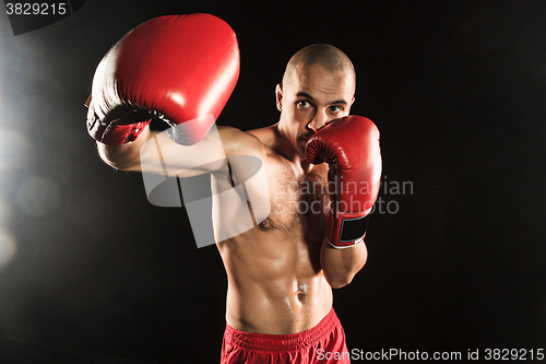 Image of The young man kickboxing on black