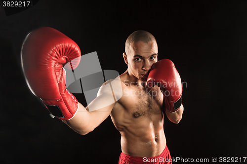 Image of The young man kickboxing on black