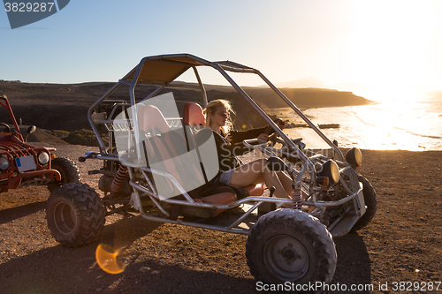 Image of Woman driving quadbike in sunset.