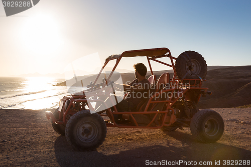 Image of Man driving quadbike in sunset.