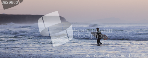 Image of Surfers on beach with surfboard.