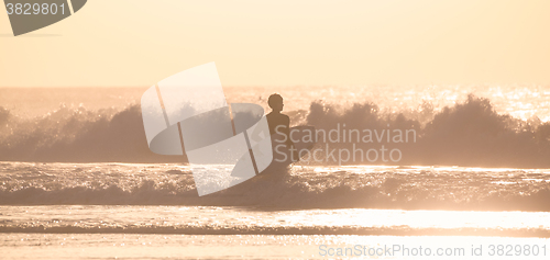 Image of Surfers on beach with surfboard.