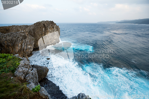 Image of Waves crashing over rock formation cliff