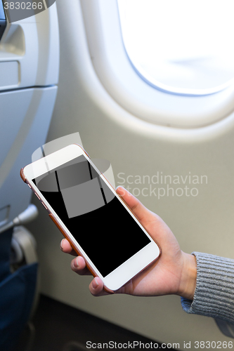 Image of Woman holding digital mobile phone at airplane
