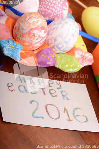 Image of Easter with eggs in nest and yellow tulips over wooden table. 