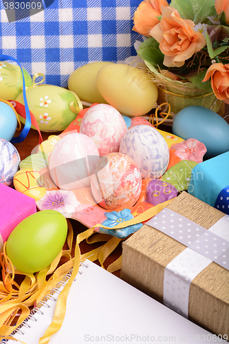 Image of Easter background with colorful eggs and yellow tulips over white wood. Top view with copy space